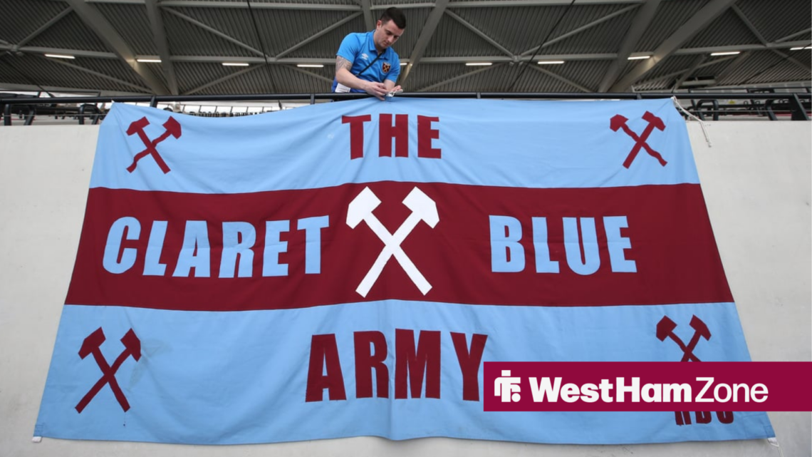 A West Ham fan hanging up a claret and blue flag at the London Stadium