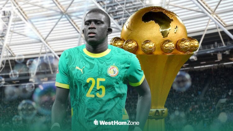 El Hadji Malick Diouf wearing a Senegal shirt, with the AFCON trophy behind him